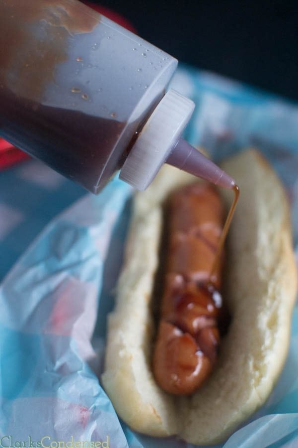 Sticky jdawg sauce being poured on top of hot dog