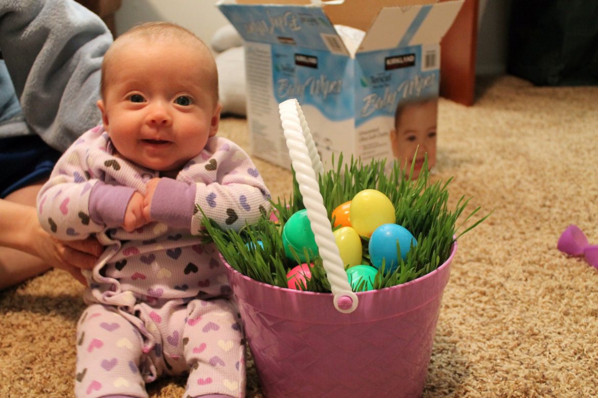 A baby sitting near a DIY Easter Grass Basket