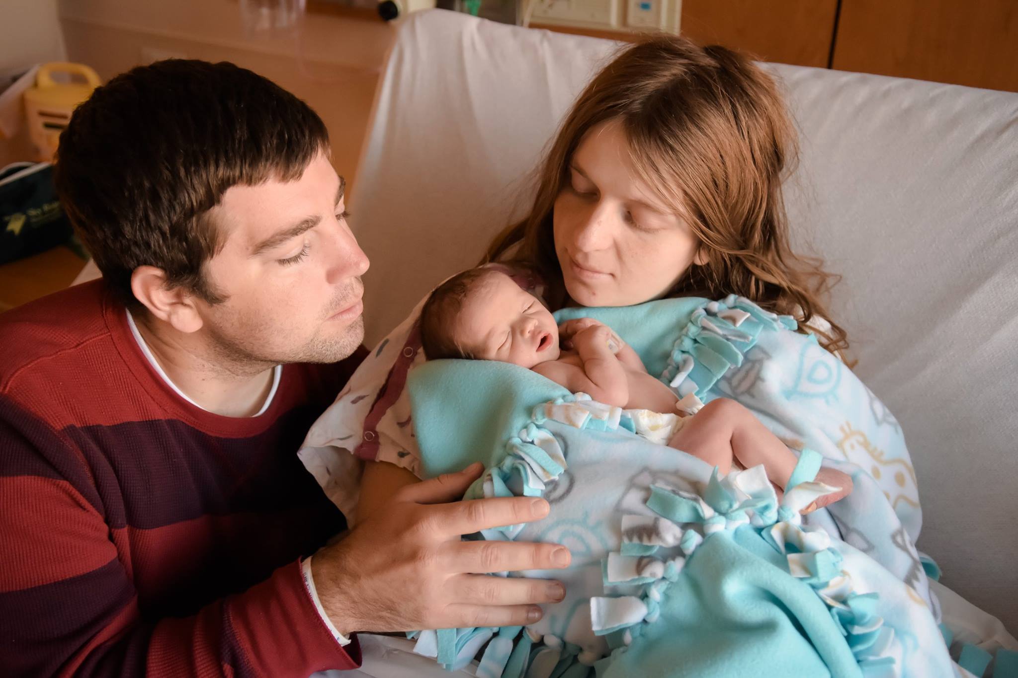 A woman holding baby, with a man on side