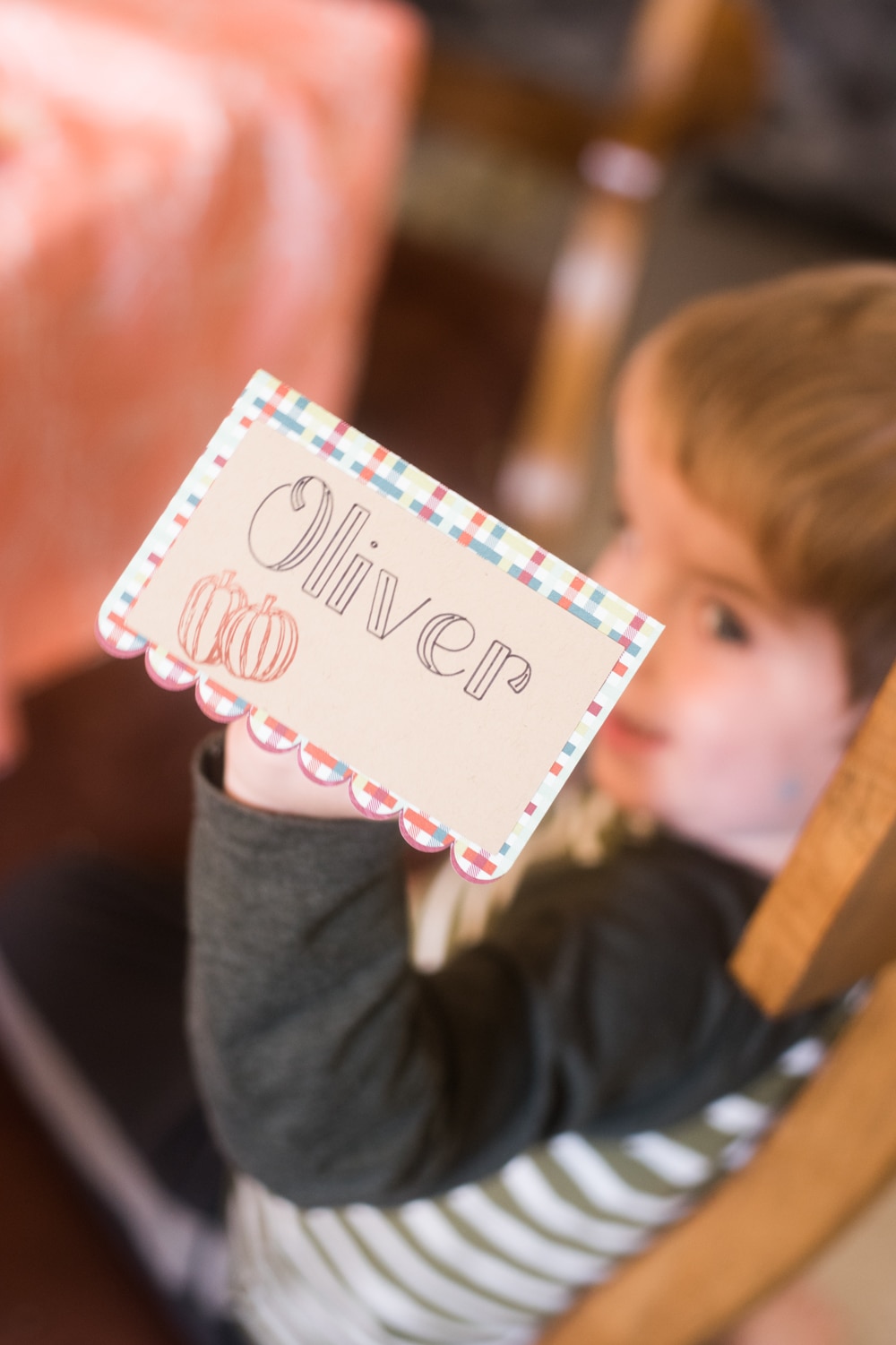 A little boy holding \"Oliver\" named card
