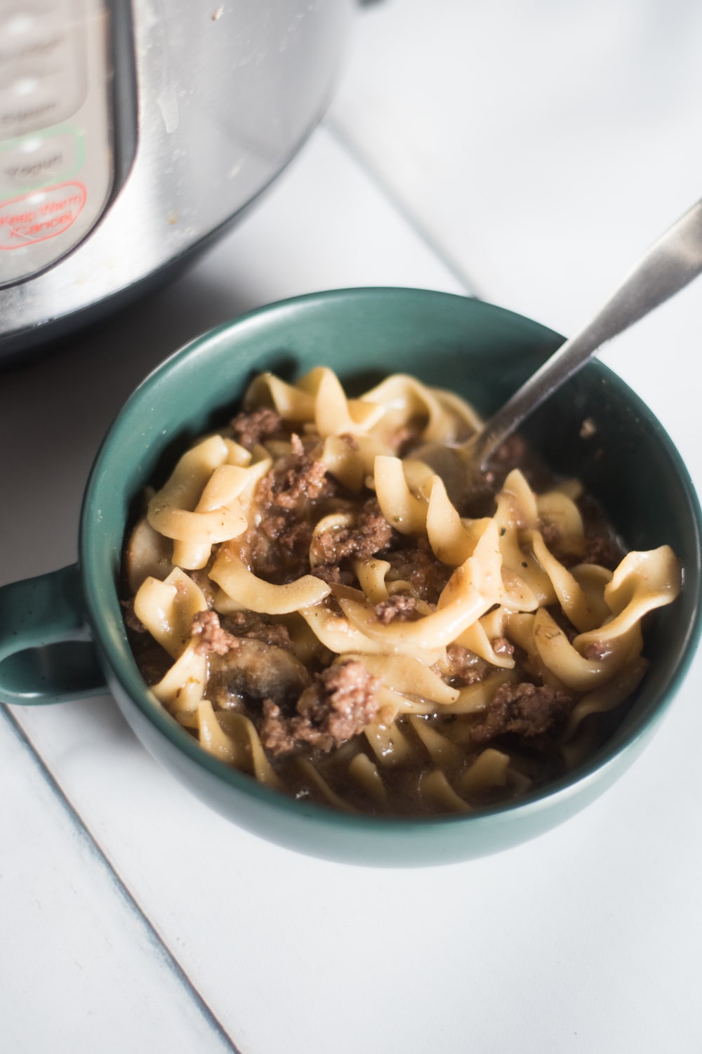 A bowl of food on a plate, with Beef Stroganoff