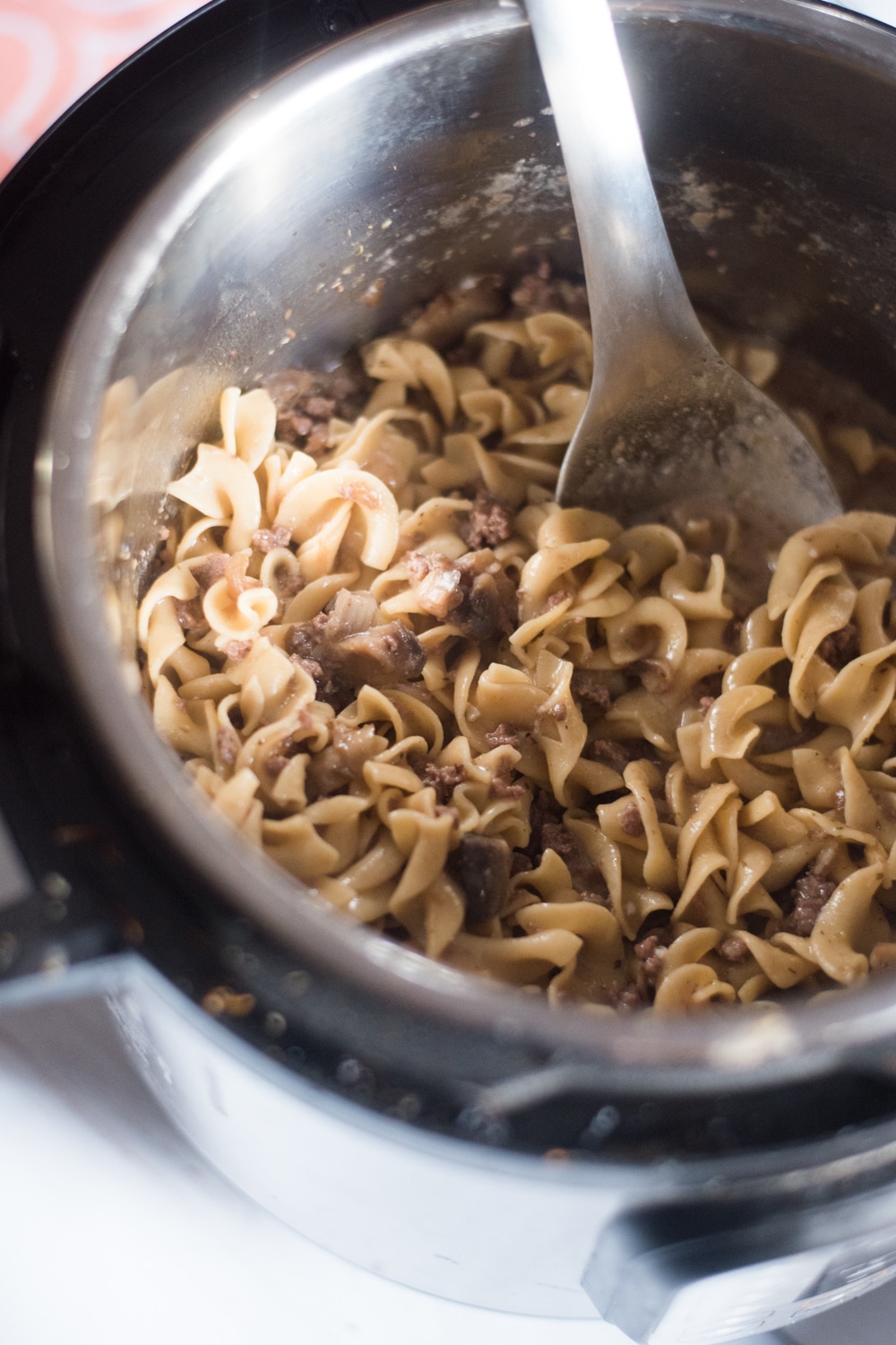 A bowl of soup and a spoon, with Beef Stroganoff and Pasta