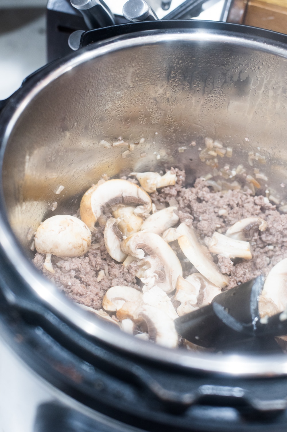 A close up of a metal pan on a stove, with Beef Stroganoff and Pasta