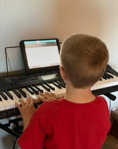 A boy sitting at a desk in front of a piano keyboard