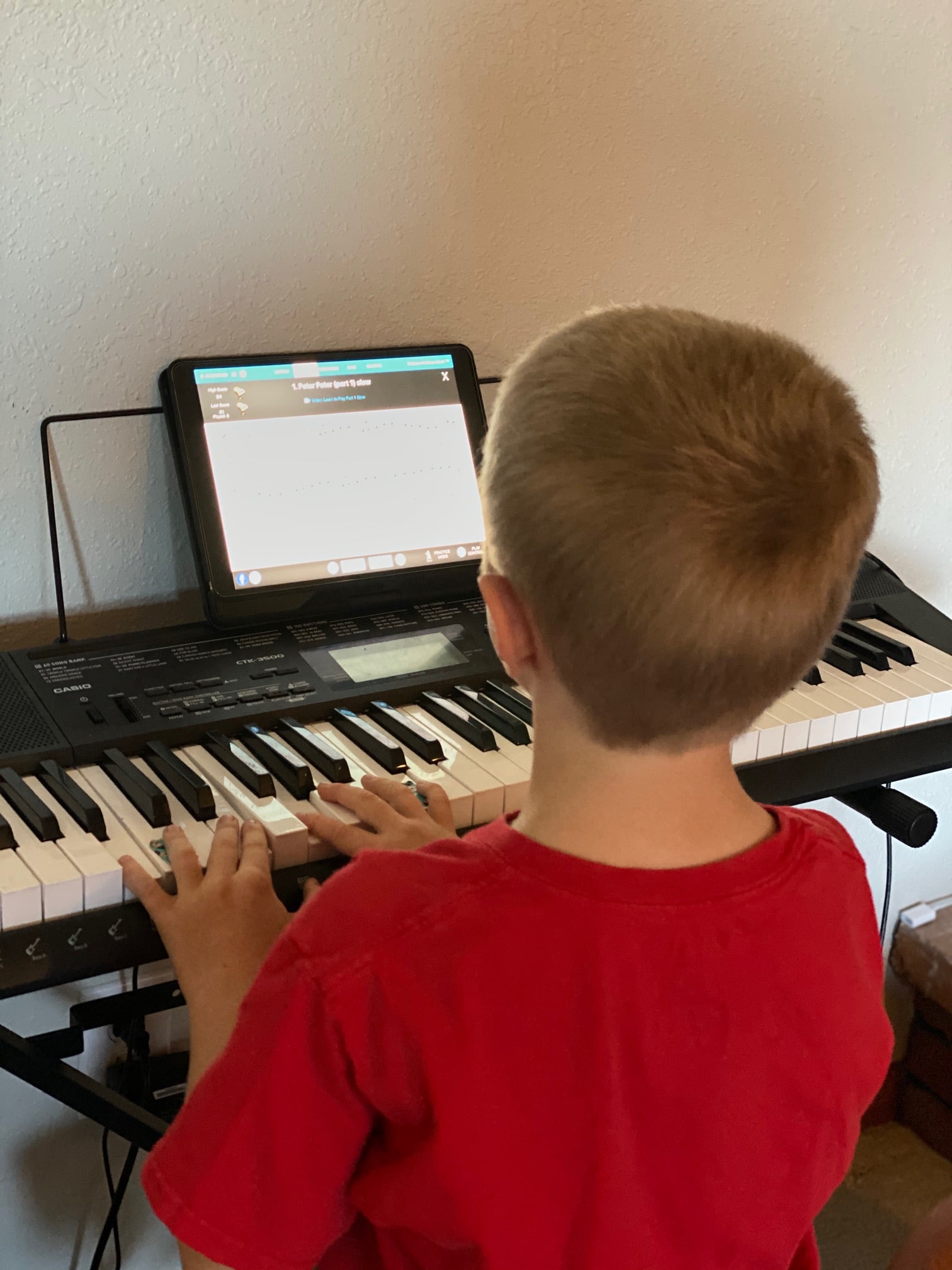 A boy sitting at a desk in front of a piano keyboard