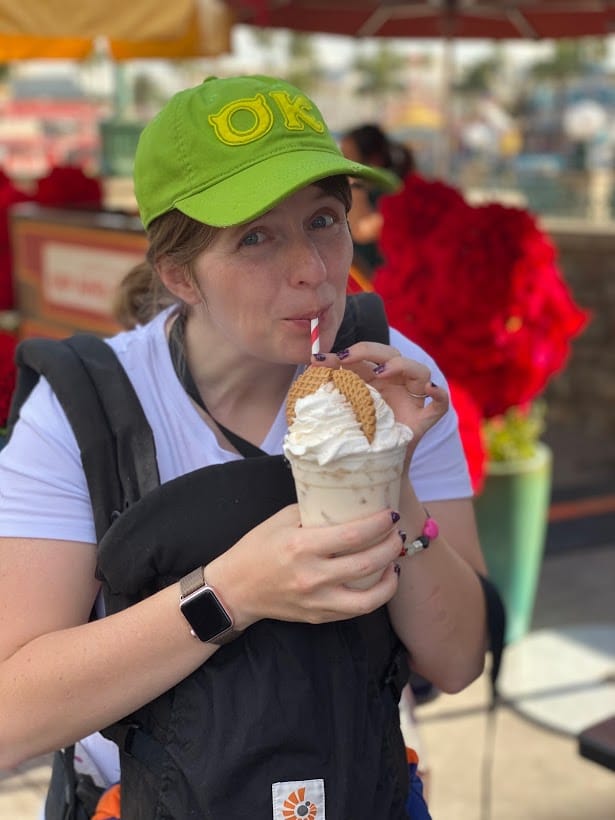 A Lady earing a hat and holding a coffee or shake