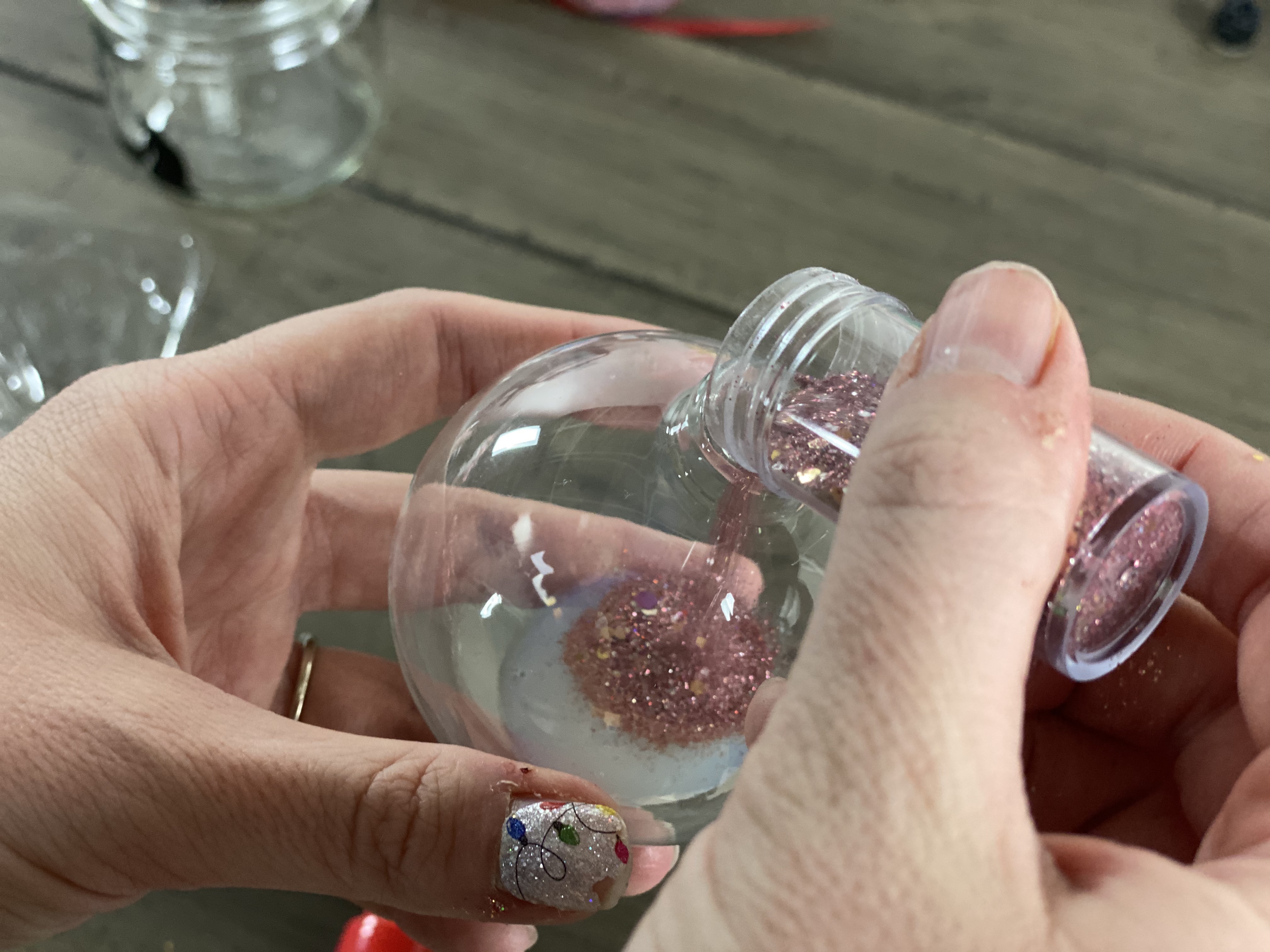 pouring glitter into glass ornament