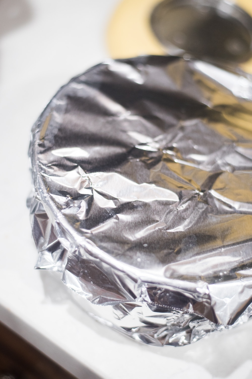 A close up of cheesecake covered with foil for baking