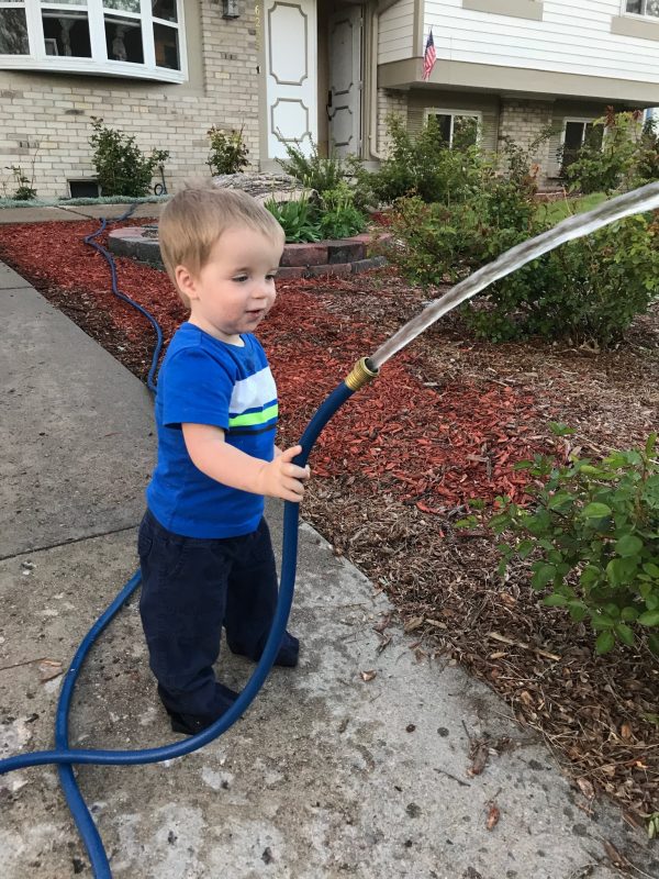 Little boy watering with hose