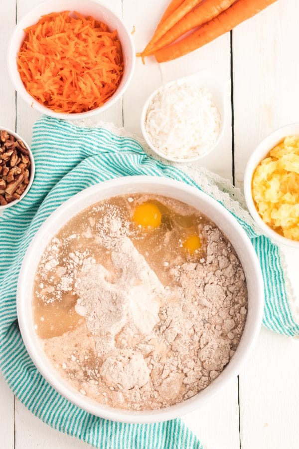 A bowl of batter, with Carrot cake ingredients on side