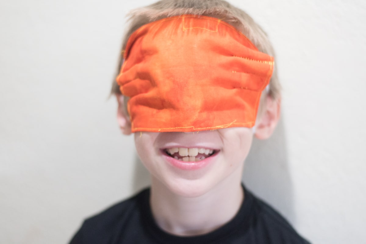 A young boy wearing a mask on eyes and smiling at the camera