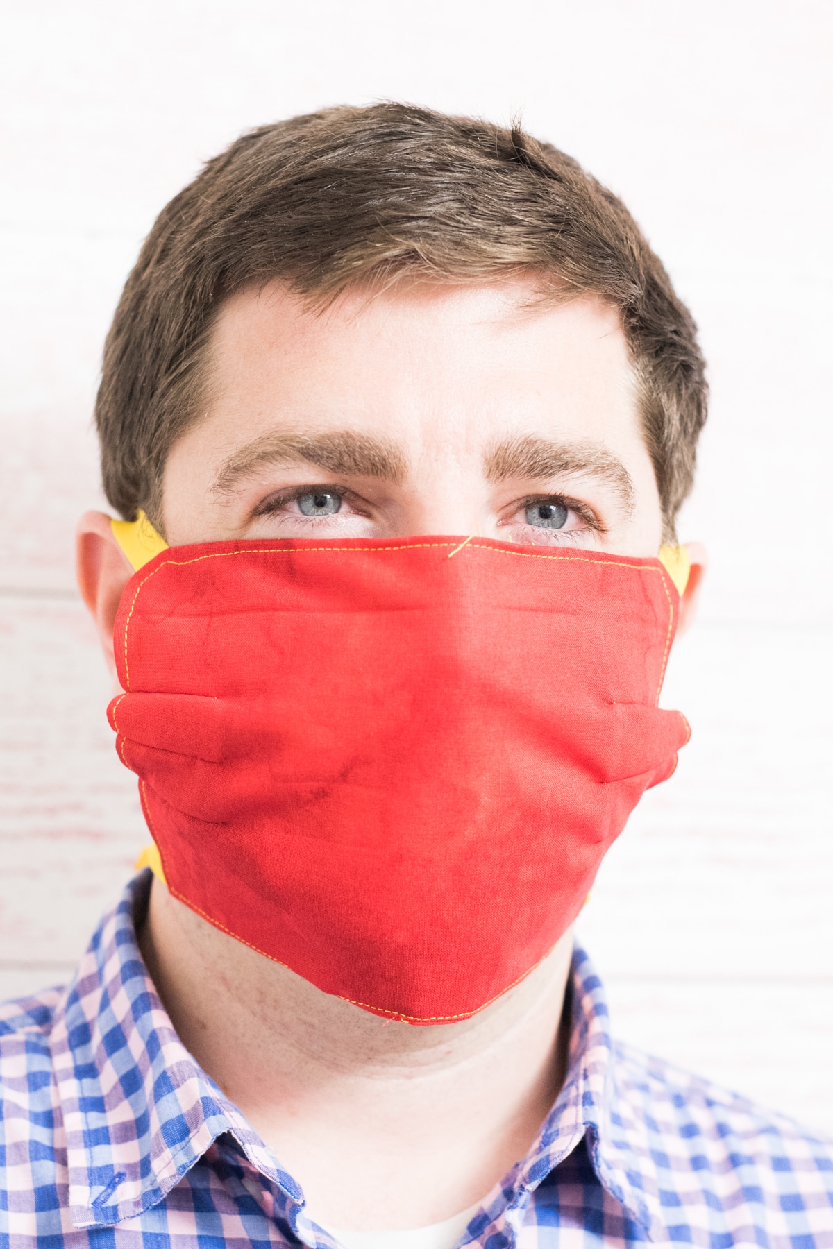 A close up of a man wearing a red mask and blue shirt
