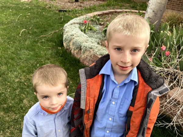 A little boy standing in front of a small child smiling at the camera