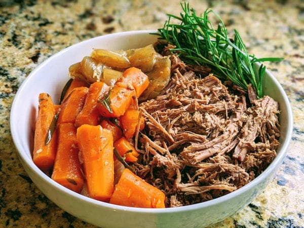 roast beef with carrots and onions and rosemary in bowl