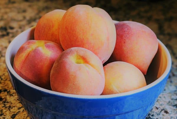 A blue bowl filled with peaches