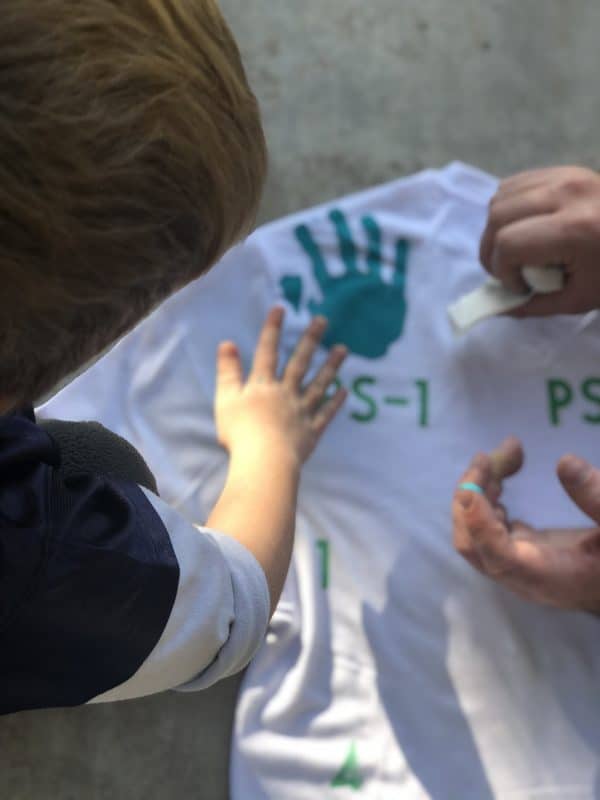 little boy putting hand print on shirt